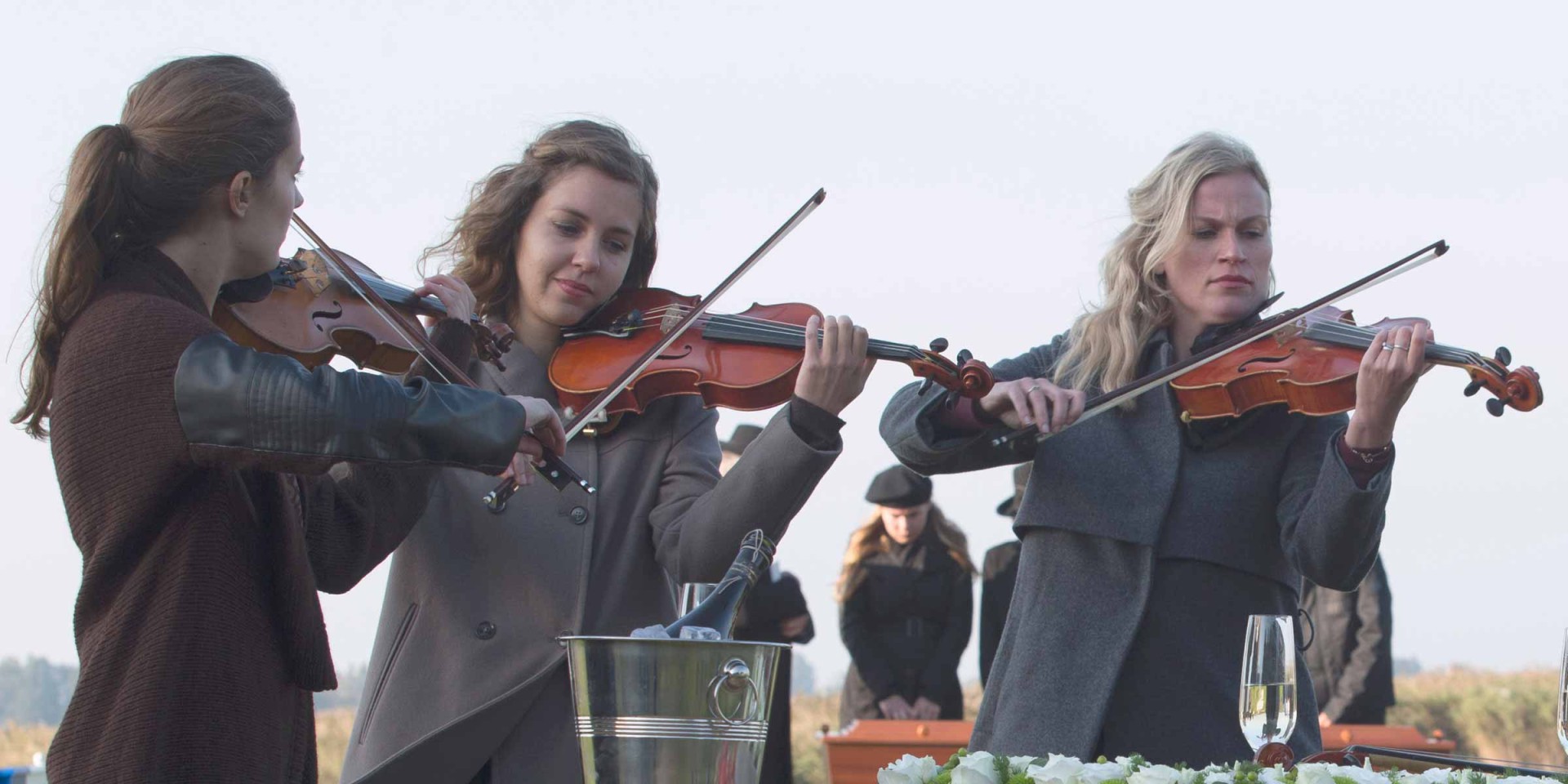 Jonge vrouwen spelen viool tijdens uitvaart